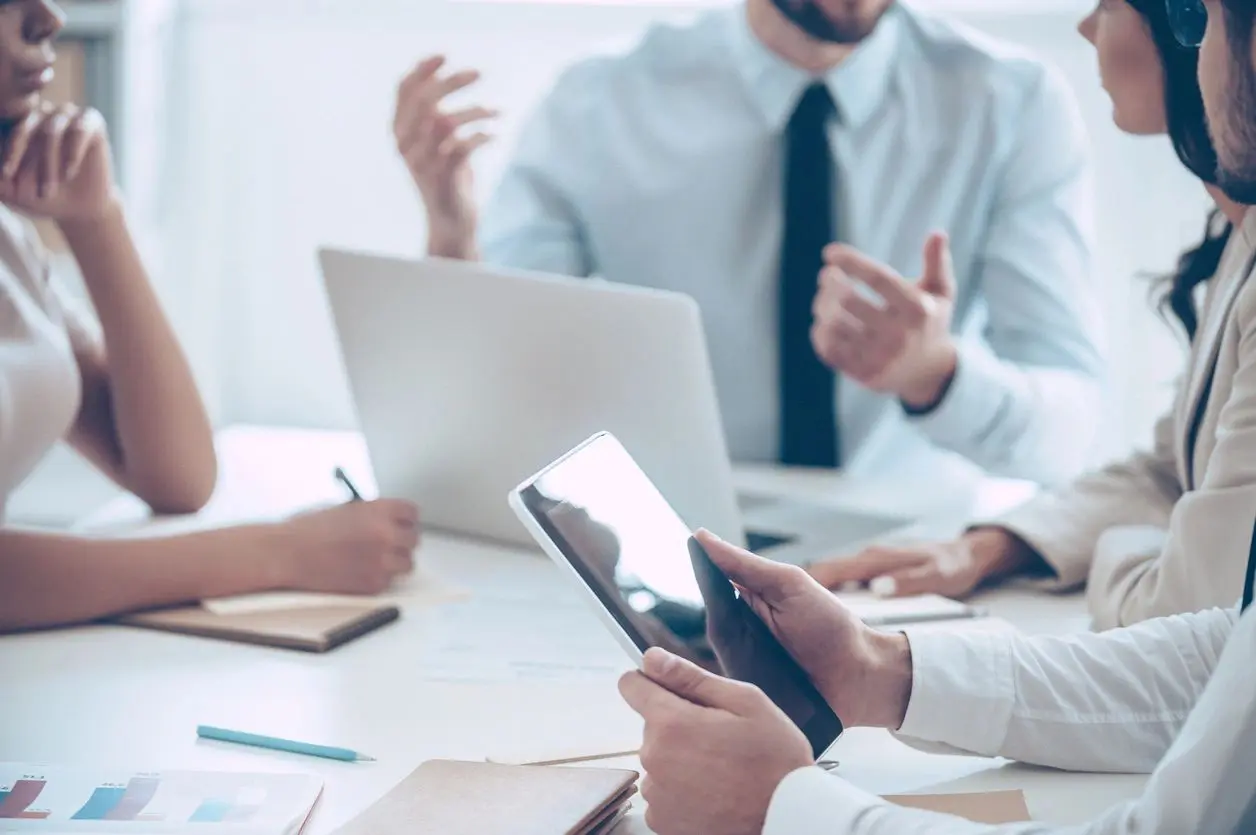 People engaged in a business meeting with laptops and tablets.