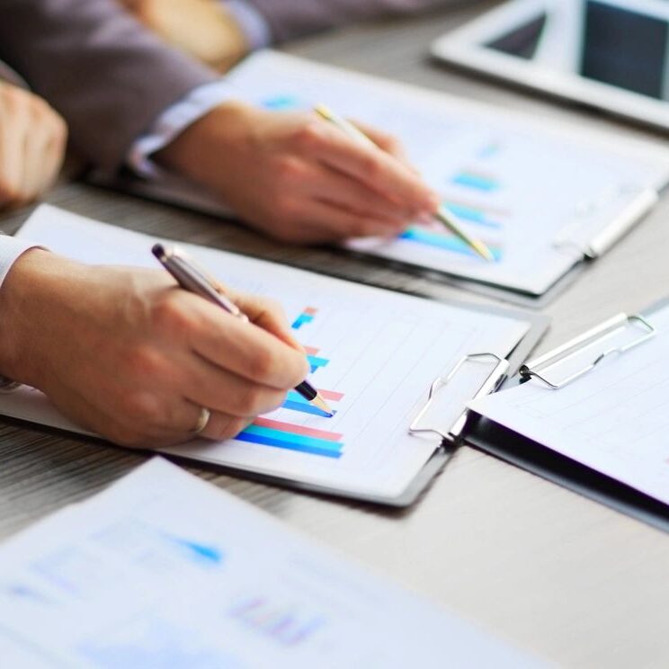 Hands analyzing financial charts and data on paper.